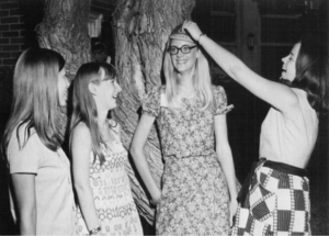 Several freshmen women laugh about how to properly wear a beanie at a lawn party thrown by Dr. 和夫人. 斯基尔斯1971年.